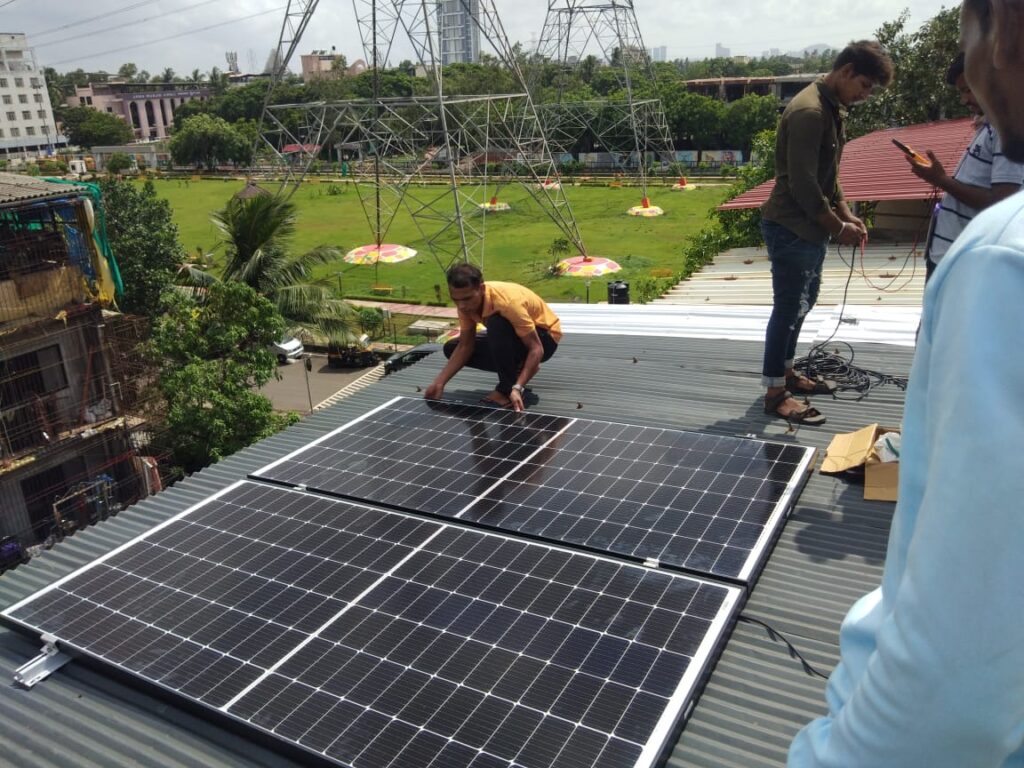 Workers engaged in the installation of solar panels on a roof in Pali, Rajasthan, promoting sustainable energy solutions.